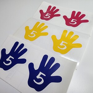May include: Five hand-shaped stickers in different colors: red, yellow, and blue. Each sticker has the number "5" printed in white.