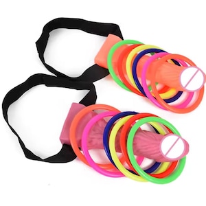 May include: Two sex toys with a pink and orange design, each featuring a series of colorful rings. The toys are connected to black straps. The rings are in various colors, including green, pink, red, yellow, and blue.