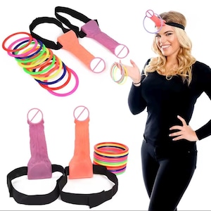 May include: An assortment of novelty party supplies, including colorful rings and phallic-shaped headbands and belt attachments in shades of pink and orange. A woman is wearing a black outfit and a headband with a similar design.