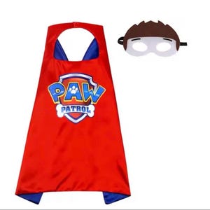 Peut inclure: Une cape rouge et bleue Paw Patrol avec le logo Paw Patrol au centre. Un masque marron et blanc est inclus. La cape est faite d'un matériau brillant.