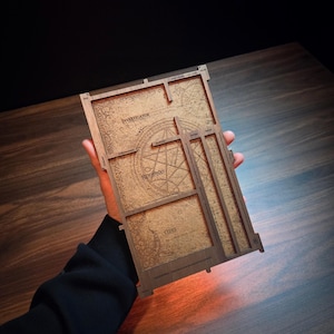 Könnte beinhalten: Ein Set aus drei Keramikbechern mit gesprenkelter, matter Oberfläche. Die Becher sind in Creme-, Hellgrau- und Dunkelgrautönen gehalten. Jeder Becher hat ein schlichtes, minimalistisches Design und einen abgerundeten Henkel.