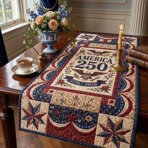 May include: A rectangular fabric table runner featuring a patriotic design with red, white, and blue colors. The center displays the text AMERICA 250, an eagle illustration, and the years 1776-2026, surrounded by star and floral patterns.