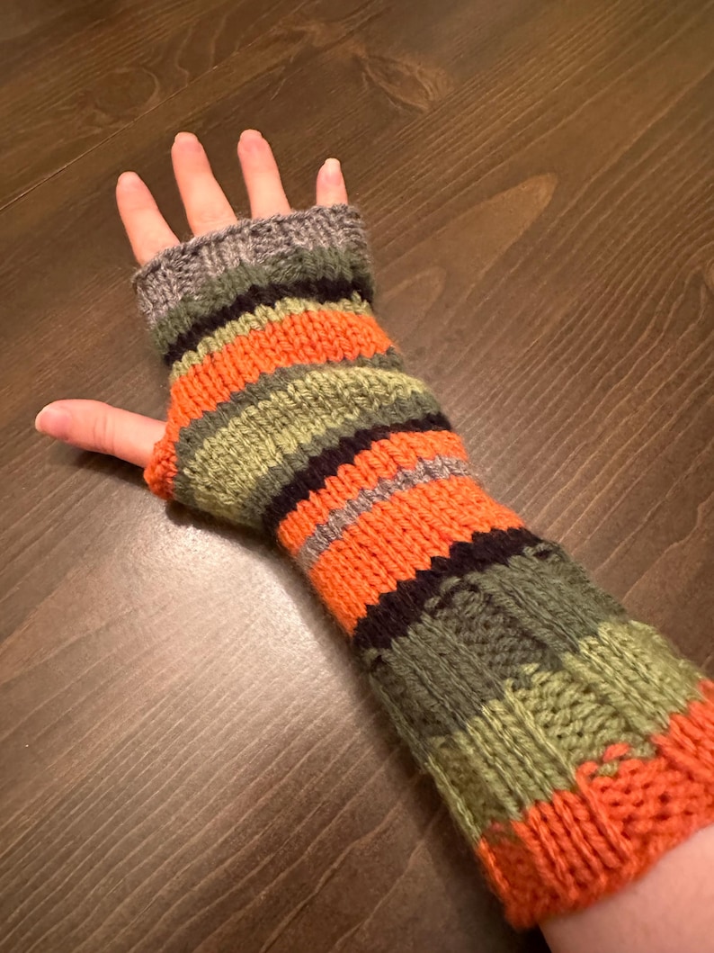 May include: Striped fingerless gloves in orange, green, black, and gray. The gloves are knitted and have a fingerless design.