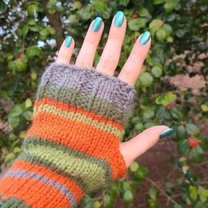May include: A pair of striped fingerless gloves in orange, green, and gray. The gloves are knitted and have a cable knit pattern on the cuff.