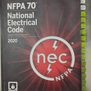 May include: A dark grey book titled "NFPA 70 National Electrical Code 2020." The cover features the text "nec" in a white circle with red accents and lightning bolt graphics. The book has labeled tabs on the side.