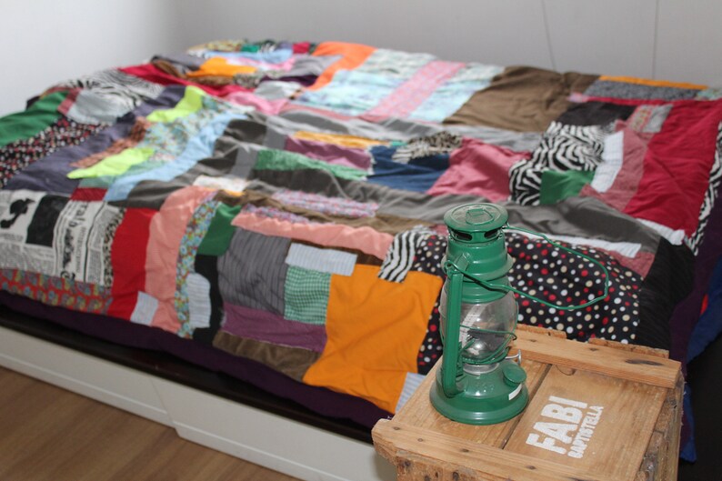 Może przedstawiać: Kolorowa kołdra w patchwork z zieloną latarnią na drewnianym stole z napisem "Fabi" i "B&auml;ckerei".