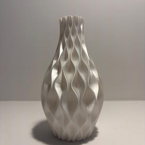 May include: A white decorative vase with a textured, wave-like pattern. The vase has a wide base that tapers to a narrow neck and flared rim. The design creates a play of light and shadow, giving the vase a modern aesthetic.