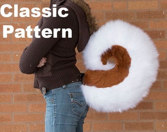 May include: A person wearing a brown jacket and blue jeans is wearing a white and brown furry tail. The tail is attached to a harness and is worn on the back. The text "Classic Pattern" is visible in the image.