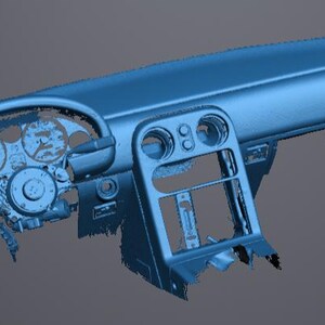 May include: A blue car dashboard with a steering wheel, gauges, and a center console. The dashboard has various openings and cutouts for components. The steering wheel is circular, and the gauges are visible. The overall design is angular.