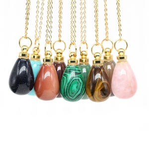 Puede incluir: Una colección de collares con colgantes de piedras preciosas. Cada collar presenta un colgante de piedra preciosa en forma de lágrima en varios colores, incluyendo negro, turquesa, rojo, verde, marrón y rosa. Los colgantes cuelgan de delicadas cadenas doradas.