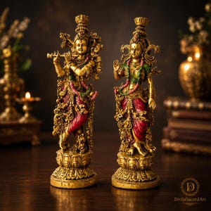 Puede incluir: Dos estatuas doradas ornamentadas sobre bases de loto. La figura de la izquierda toca una flauta, vistiendo una prenda roja con detalles verdes. La figura de la derecha tiene una mano levantada, vistiendo una parte superior verde y falda roja.