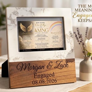 May include: A rectangular picture frame featuring a white marble top section and a dark wood bottom section. The wood is engraved with the names Morgan & Zack, the word Engaged, and the date 08.08.2026. A printed card inside displays text and graphics.