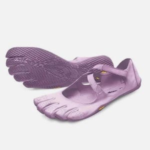 May include: A pair of light purple five-toe shoes featuring a Mary Jane style strap across the top. The shoes have a textured, flexible sole with individual toe compartments and a smooth upper material, showcasing a distinct minimalist design.