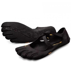 May include: A pair of black five-toe shoes featuring individual toe compartments, a textured rubber sole, and a crisscross strap across the top. The shoes include small yellow branding accents on the side and interior sole, with a low-profile design.