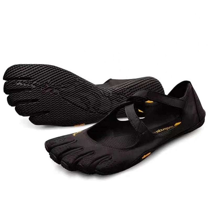 May include: A pair of black five-toe shoes featuring individual toe compartments, a textured rubber sole, and a crisscross strap across the top. The shoes include small yellow branding accents on the side and interior sole, with a low-profile design.