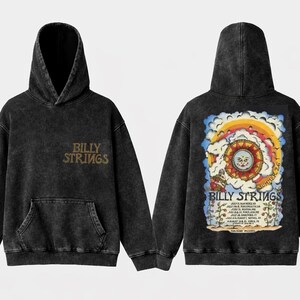 May include: A black acid-wash hoodie featuring a front kangaroo pocket and the text Billy Strings in gold. The back displays a colorful graphic of a sun, clouds, and a tour schedule with the text Billy Strings Summer 26 and various locations.
