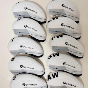 以下が含まれることがあります： 白のTaylorMadeゴルフヘッドカバーのコレクション。各カバーにはTaylorMadeのロゴ、グレーのアクセント、黒のトリムが付いています。カバーには5、6、7、LW、PW、SW、AWなどの数字と文字が記載されています。