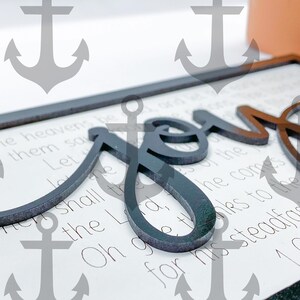 May include: A black wooden sign with the word "Joy" in large, stylized lettering. The sign has a white background with a Bible verse printed on it: "Let the heavens be joyful, let the earth be glad; let the sea roar and all that is in it." 1 Chronicles 16:31-34.