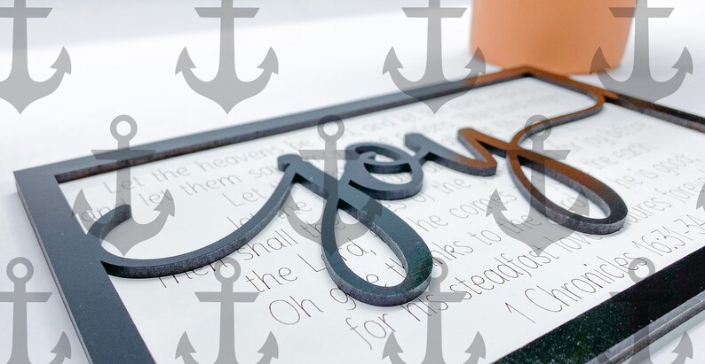May include: A black wooden sign with the word "Joy" in large, stylized lettering. The sign has a white background with a Bible verse printed on it: "Let the heavens be joyful, let the earth be glad; let the sea roar and all that is in it." 1 Chronicles 16:31-34.