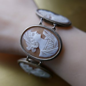 Puede incluir: Un brazalete de cadena de plata con tres camafeos ovalados que presentan retratos de mujeres en camafeo blanco. Los camafeos están engastados en marcos de plata con un acabado texturizado.