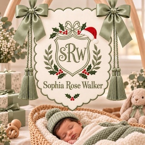 Könnte beinhalten: Ein cremefarbener Wandbehang aus Stoff mit gewelltem Rand, bestickt mit einem Wappen, dem Monogramm SRW, Stechpalmenblättern, roten Beeren und einer Weihnachtsmütze. Das Banner ist an zwei salbeigrünen Satinschleifen mit passenden Quasten befestigt.