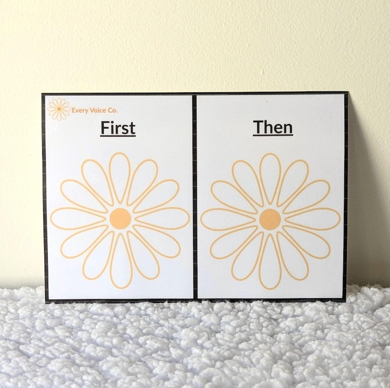 May include: Two white cards with black borders, featuring daisy illustrations and the words "First" and "Then." The daisy design is in light orange, with the text in black. The cards are from "Every Voice Co."