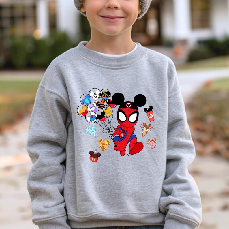 May include: A gray sweatshirt featuring a cartoon character that is a hybrid of Spider-Man and Mickey Mouse. The character holds a bunch of balloons with Disney character designs. Additional Disney-themed graphics, like ice cream and donuts, are also present.