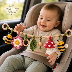 May include: A crochet baby stroller toy arch featuring a beige cord with wooden rings at each end. Hanging from the cord are six crocheted items: a yellow and black bee, a pink flower, a wooden ring, a green leaf, a wooden bead, and a red mushroom.