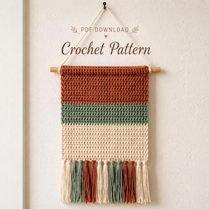 May include: A crochet wall hanging with a wooden dowel and tassels. The design features horizontal stripes in rust, olive green, and cream colours. The text "PDF DOWNLOAD" and "Crochet Pattern" are displayed on the wall hanging.