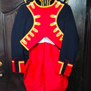 Peut inclure: Un uniforme de style militaire, composé d'une veste noire avec des détails rouges et dorés. La veste est ornée de boutons dorés et d'un col montant. L'ensemble comprend un pantalon rouge. Idéal pour une reconstitution historique ou un costume.