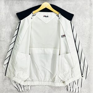 May include: White and black Fila jacket with a black collar and black vertical stripes on the sleeves. The jacket has a mesh lining and two front pockets. The Fila logo is visible on the chest and sleeve.