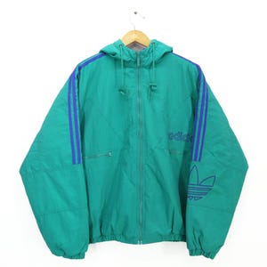 May include: Teal hooded jacket with blue stripes on the sleeves and the Adidas logo. The jacket features a full zip, two front pockets, and drawstrings on the hood. The Adidas logo is on the right side of the jacket.