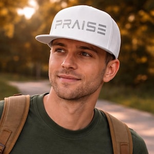May include: White baseball cap with the word "PRAISE" in gray block letters across the front. The cap has a flat brim and is worn by a person. The person is wearing a green shirt and a brown backpack.