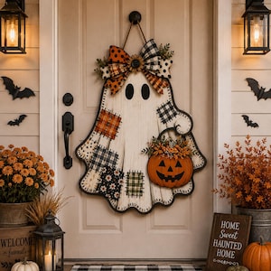 May include: A ghost-shaped wooden door hanger featuring a white distressed finish, patchwork fabric accents in orange and black patterns, a large decorative bow, and a jack-o'-lantern bucket filled with small orange flowers and greenery.