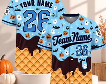 May include: A light blue baseball jersey featuring a repeating Halloween pattern of pumpkins, ghosts, bats, and sweets. The bottom section displays a brown chocolate drip over a waffle cone texture. The front shows Team Name and number 26.