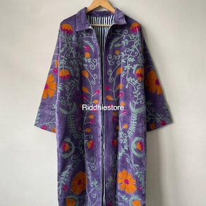 Può includere: Un cappotto viola a maniche lunghe con un motivo floreale ricamato in arancione, rosa e verde chiaro. Il capo presenta un colletto, un'apertura frontale e una fodera a righe blu e bianche visibile. Il testo Riddhiestore è stampato al centro.