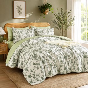 May include: A bedding set featuring a white duvet cover and two matching pillow shams with a green botanical print of flowers, leaves, and birds. The set includes a solid light green flat sheet and is displayed on a bed with a cane headboard.
