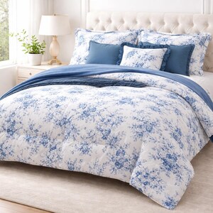 May include: A bed with a white floral patterned comforter and matching pillowcases. The comforter and pillowcases have a blue floral design. There are also solid blue pillows and a blue throw blanket. The bed has a white upholstered headboard.