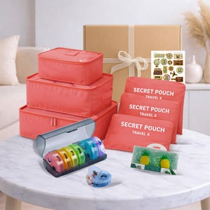 Könnte beinhalten: Ein korallenfarbenes Reiseset mit drei Aufbewahrungstaschen, drei "Secret Pouch"-Taschen und einer Geschenkbox mit Schleife. Außerdem abgebildet sind ein Wochen-Pillen-Organizer, eine kleine Pillendose und zwei augenförmige Augenmasken.