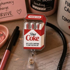 Pu&ograve; includere: Una scena da scrivania a tema infermieristico. Include una tazza di caff&egrave;, una lattina di Diet Coke, uno stetoscopio e un badge con la scritta "RN Registered Nurse". Ci sono anche post-it con testo come "Charting" e "Caffeine, Compassion & Chaos".
