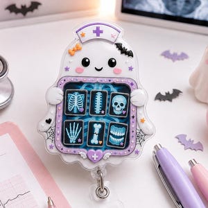 May include: A ghost-shaped badge reel featuring a nurse cap, holding a frame with six medical X-ray images of bones and teeth. The ghost has a white body, black eyes, pink cheeks, and a purple border with spiderweb accents. A metal clip is attached below.