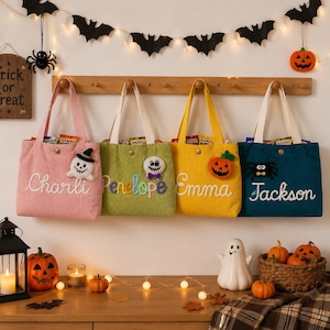 May include: Four corduroy tote bags in pink, green, yellow, and teal, each featuring a white handle, a snap closure, and a personalized name embroidered in white or colorful script. Each bag displays a felt Halloween-themed applique.
