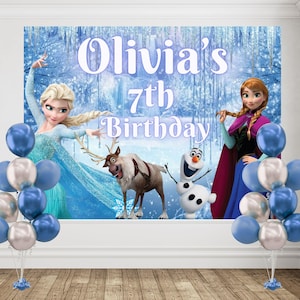Puede incluir: Un tel&oacute;n de fondo rectangular con Elsa, Anna, Sven y Olaf sobre un fondo de bosque nevado con el texto Olivia's 7th Birthday. Dos grupos de globos azules y plateados est&aacute;n colocados a la izquierda y derecha de la pantalla.