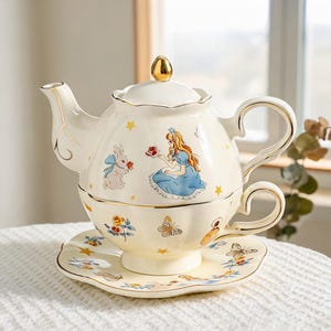 Peut inclure: Un service à thé en céramique crème pour une personne, composé d'une théière empilable sur une tasse et une soucoupe. L'ensemble est orné d'illustrations d'une fille aux longs cheveux, d'un lapin, de papillons, de roses et d'étoiles dorées.