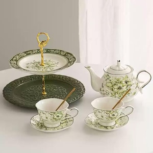 May include: A set of three ceramic mugs with a speckled, matte finish. The mugs are in shades of cream, light gray, and dark gray. Each mug has a simple, minimalist design and a rounded handle.