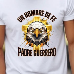 May include: A white t-shirt featuring a graphic of a bald eagle head centered over a glowing gold cross. The text "UN HOMBRE DE FE" is arched above the eagle, and "PADRE GUERRERO" is printed in black lettering below the eagle design.