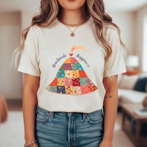 Puede incluir: Una taza de cerámica blanca con un asa negra y el texto "But First, Coffee" en negrita negra. La taza se encuentra sobre un fondo neutro, resaltando su diseño simple.