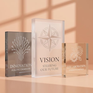 May include: Three rectangular acrylic blocks with etched designs. The left block is dark gray with a tree circuit graphic and the text INNOVATION FUELING CREATIVITY. The center block is frosted with a compass rose and VISION STEERING OUR FUTURE. The right block is clear with a gear and leaf graphic and COLLABORATION SYNERGY IN ACTION.