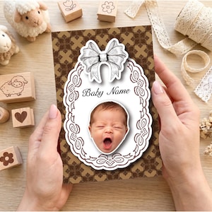 May include: A rectangular card featuring a brown background with a repeating geometric pattern. Centered is a white oval frame with a decorative border and a bow at the top. The text Baby Name is printed above a photograph of a yawning infant.