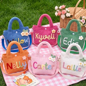 May include: Six small corduroy tote bags in blue, hot pink, green, orange, light pink, and white. Each bag features a white snap closure, a matching shoulder strap, and a personalized name in colorful fabric letters with small floral accents.